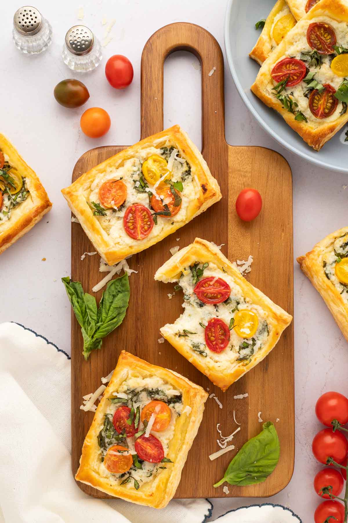 Puffed pastry tomato tart on a wooden serving board.