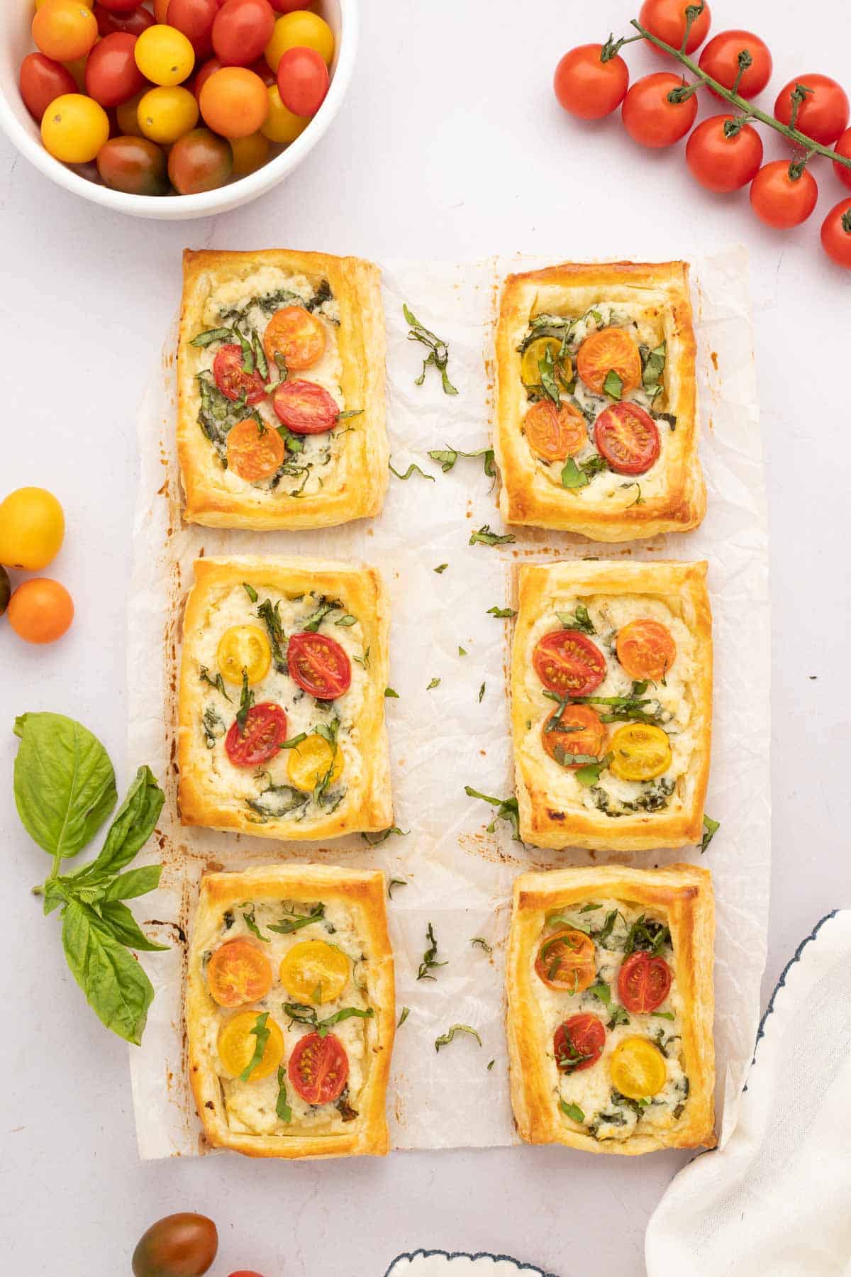 Puff pastry tomato tart set on parchment paper and sprinkled with fresh basil