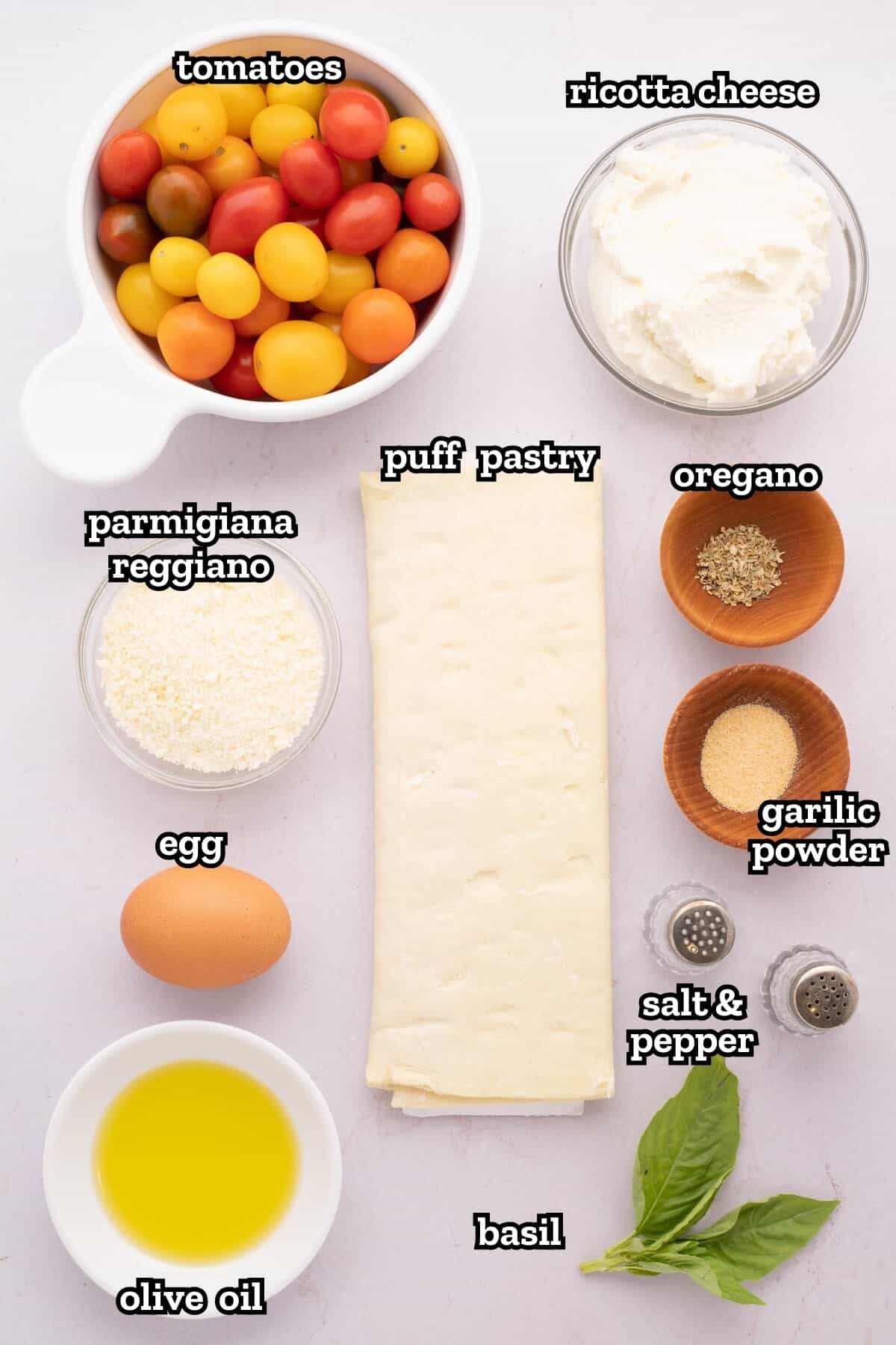 Labeled ingredients needed to make a tomato tart with puff pastry.