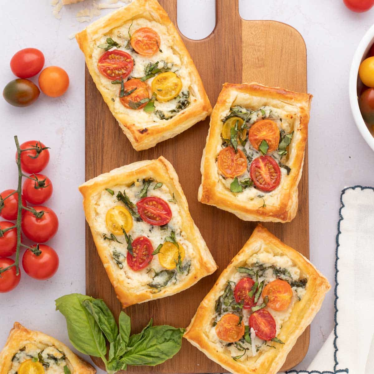 Tomato tart with puff pastry on a wooden serving board.