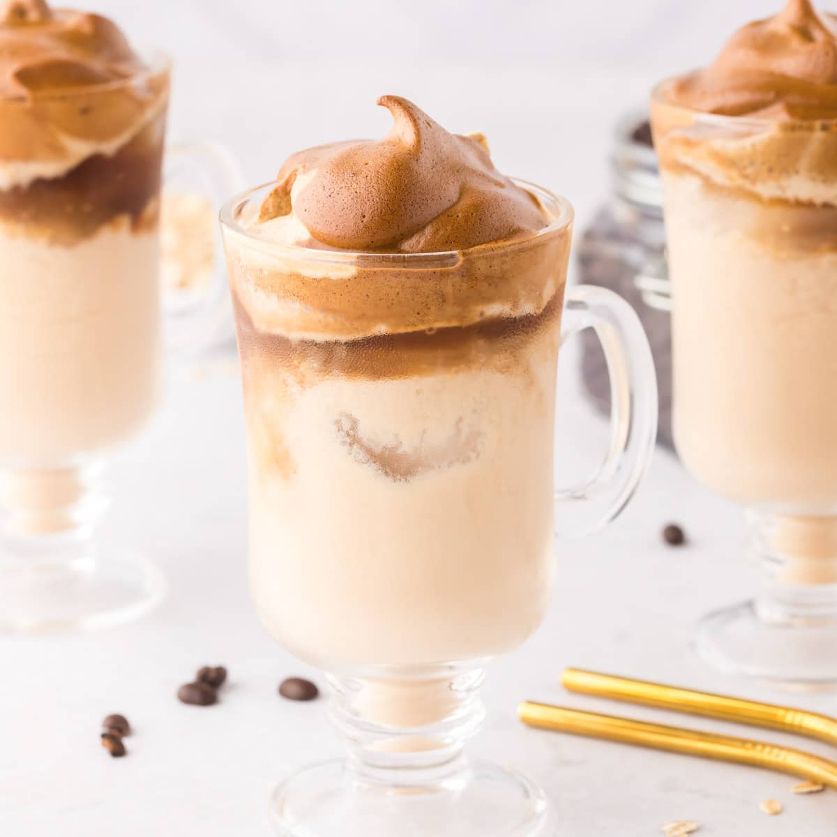 A clear coffee mug filled with iced milk topped with whipped sweetened coffee.