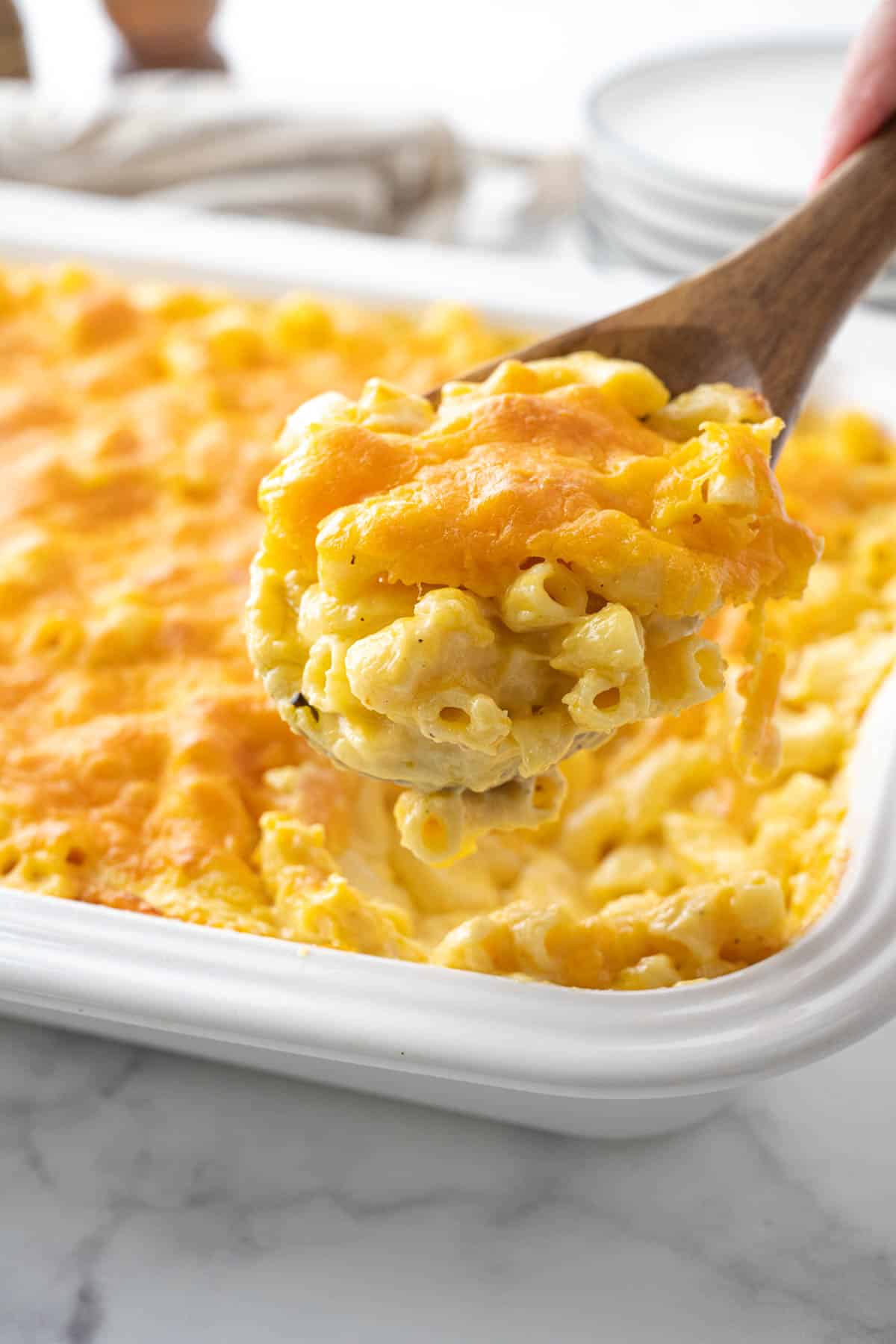 Removing a scoop of macaroni and cheese from a casserole dish.