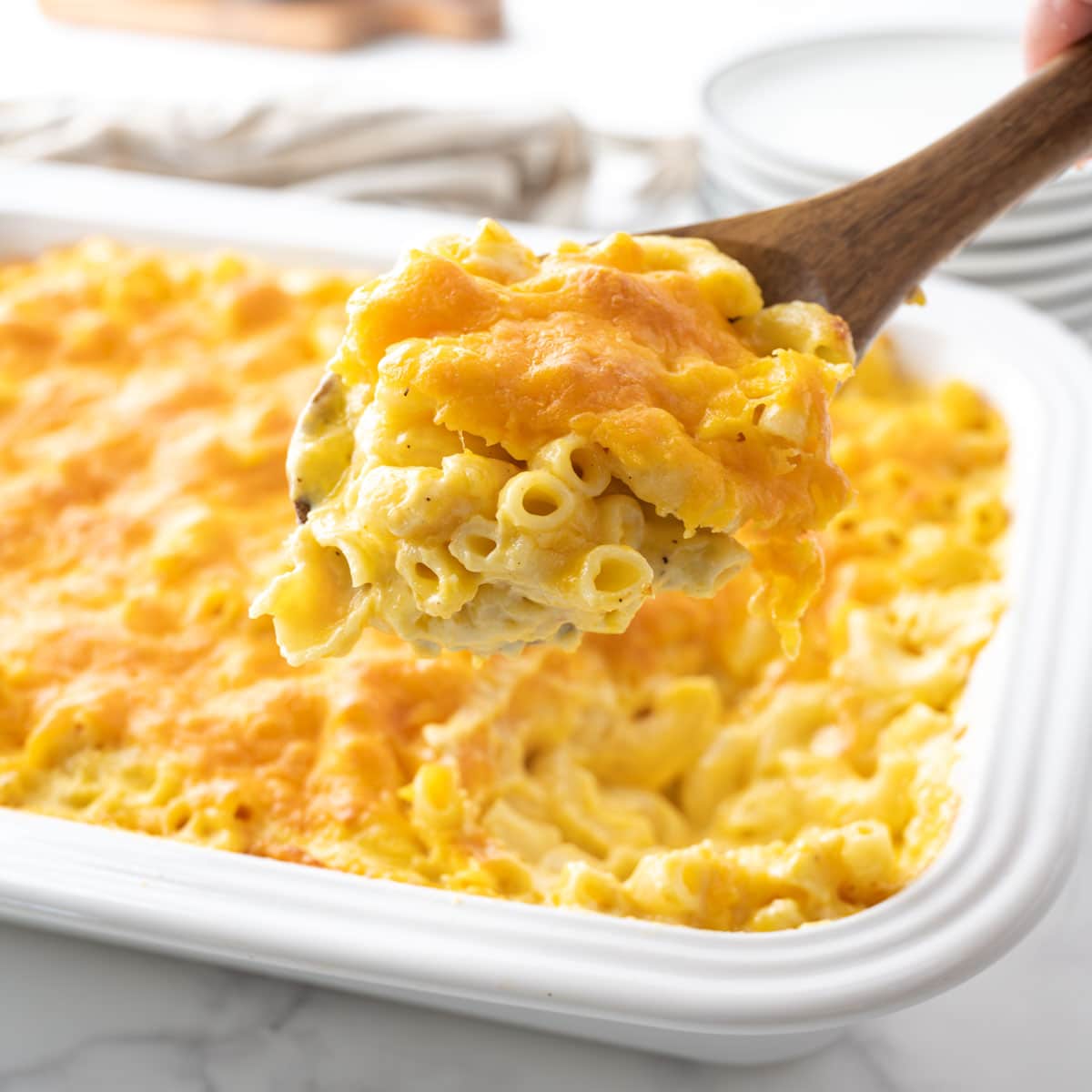 Removing a scoop of baked macaroni and cheese from a casserole dish.