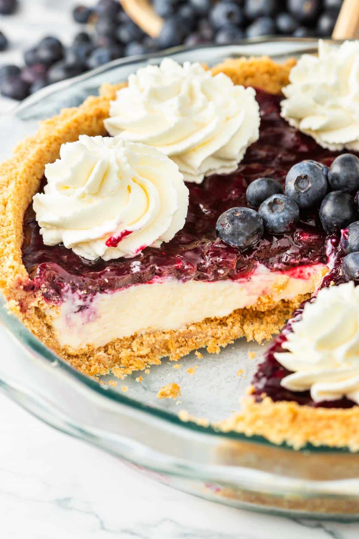 A blueberry pie with cheesecake filling with a slice removed.