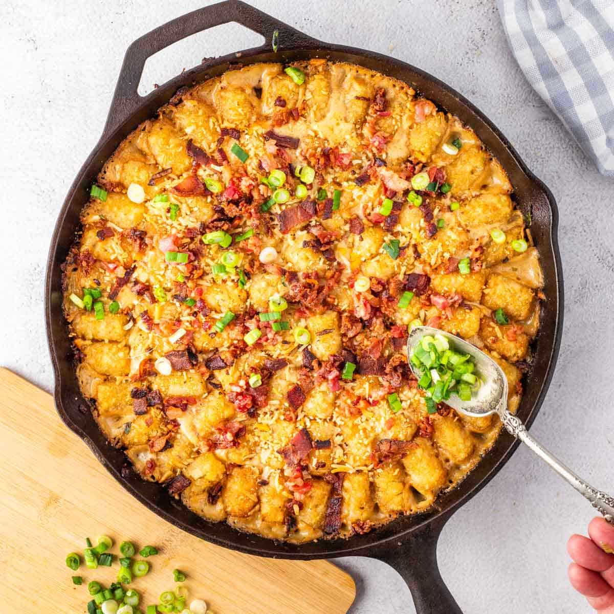 A cast-iron skillet filled with cowboy casserole topped with tater tots.