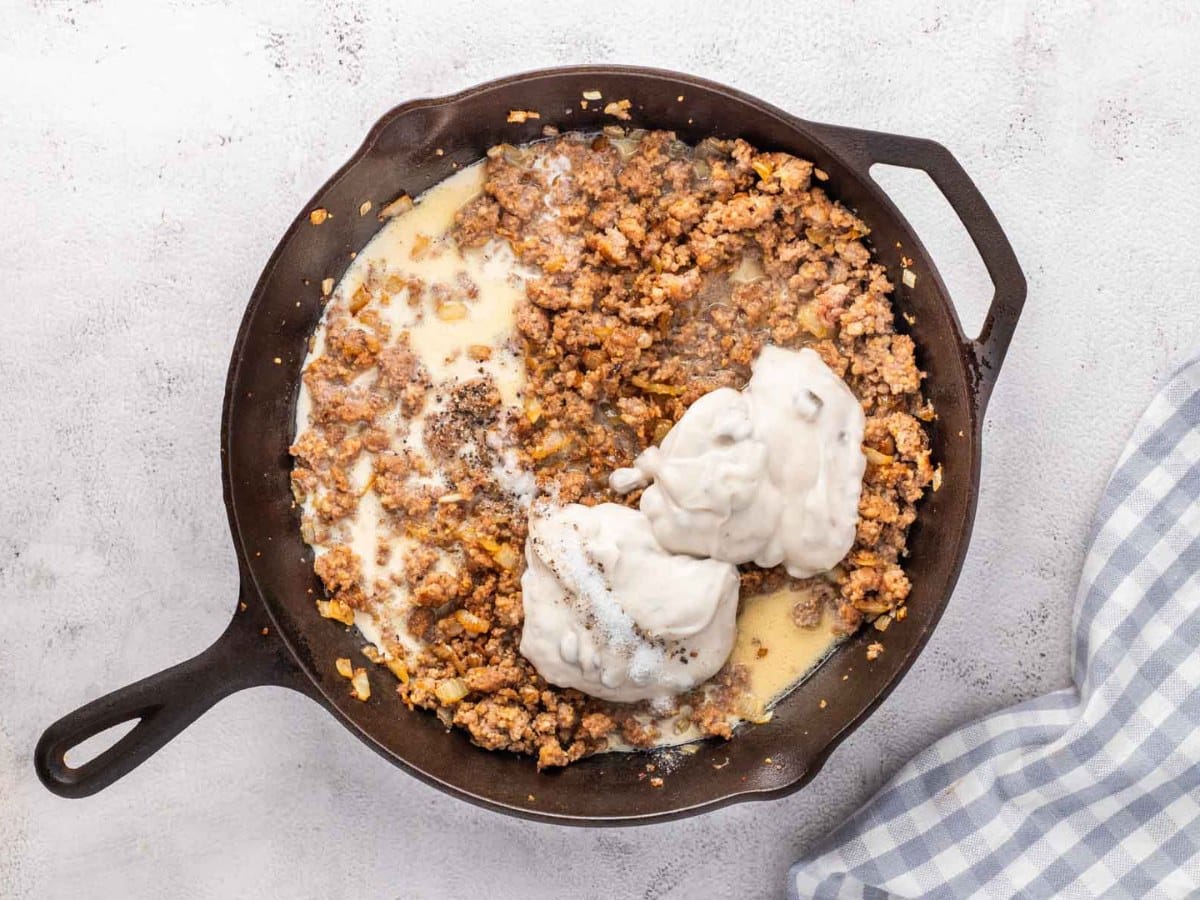 Cooke ground sausage in a skillet with milk, cream of mushroom, salt and pepper added to the skillet.