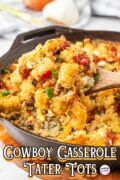 Cowboy Casserole with Tater Tots is served in a skillet and scooped up with a wooden spoon to get all the golden layers.