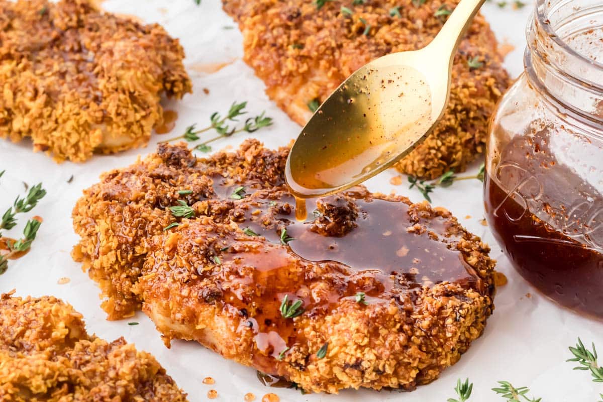 Chicken cutlets with hot honey sauce being drizzled over them.