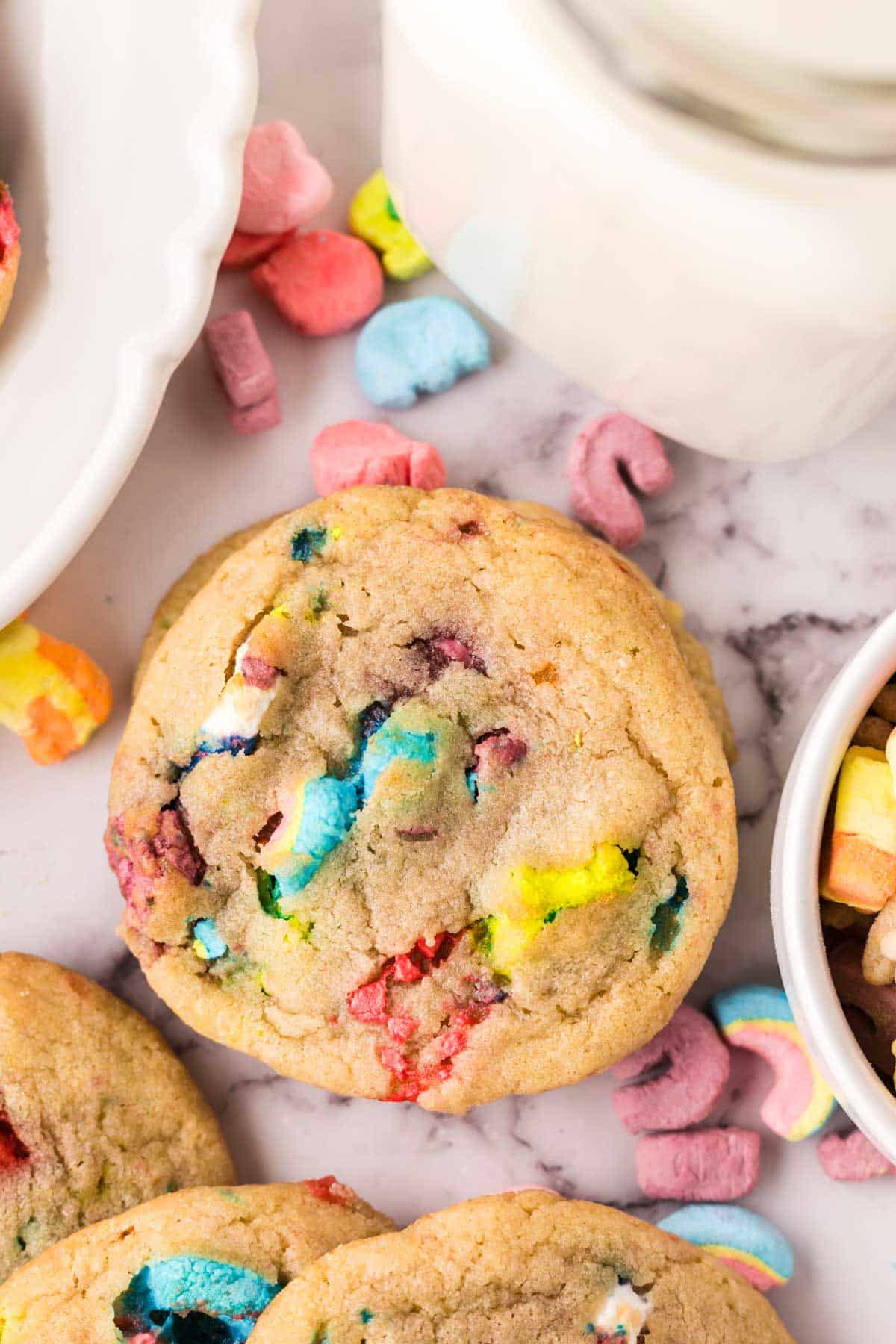 Lucky charms cookies with cereal marshmallows scattered around them.