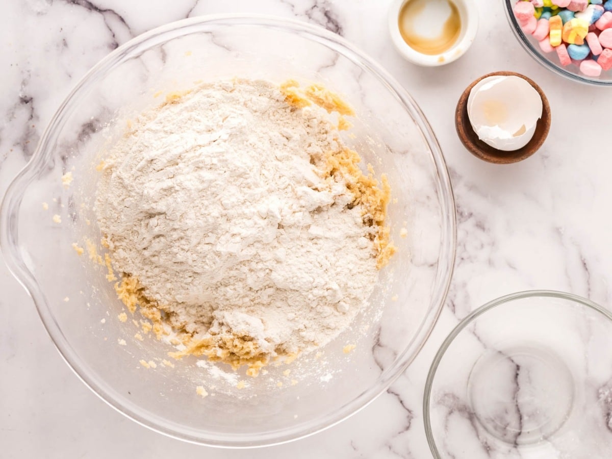 Flour and baking soda added to a bowl of cookie dough.