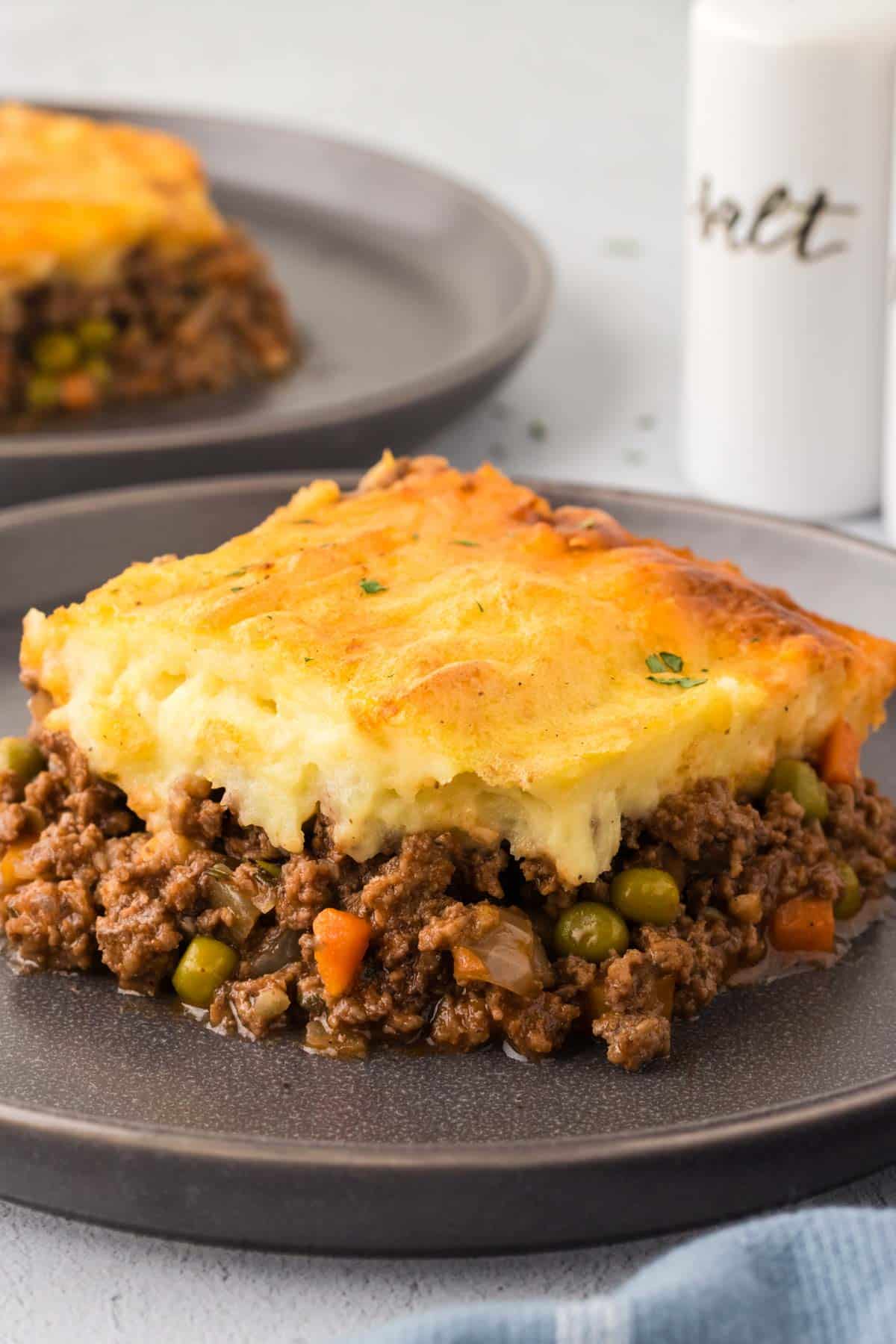 A slice of Shepherd's Pie on a dark grey plate.