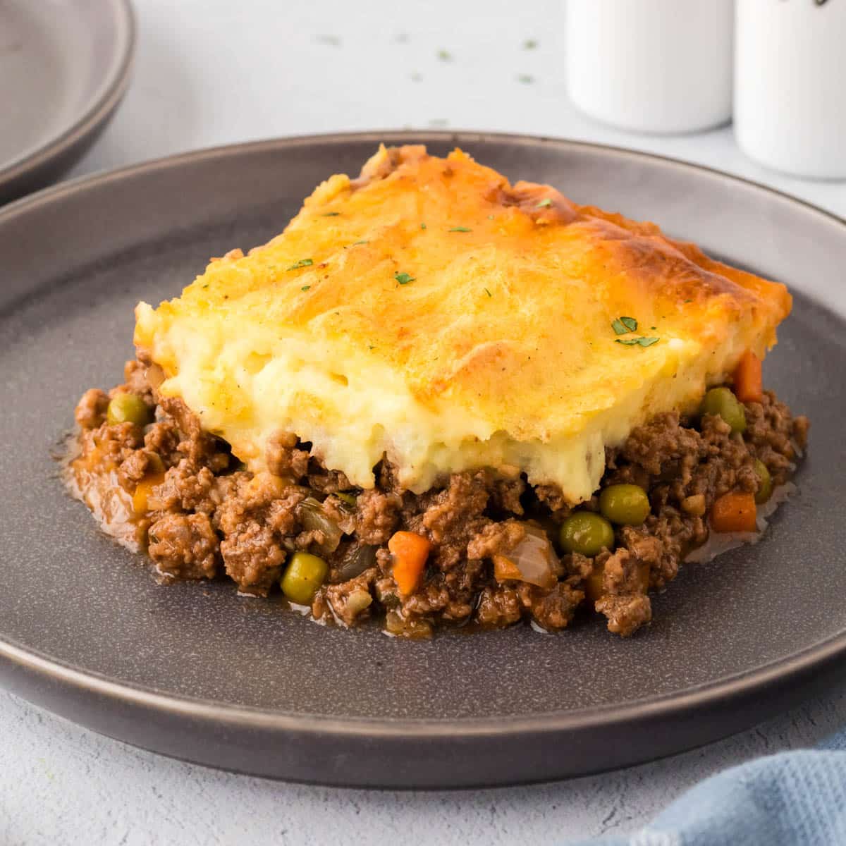 A slice of Shepherd's Pie on a dark gray plate.