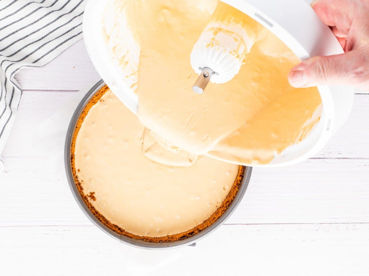 Pouring cheesecake filling into the crust.