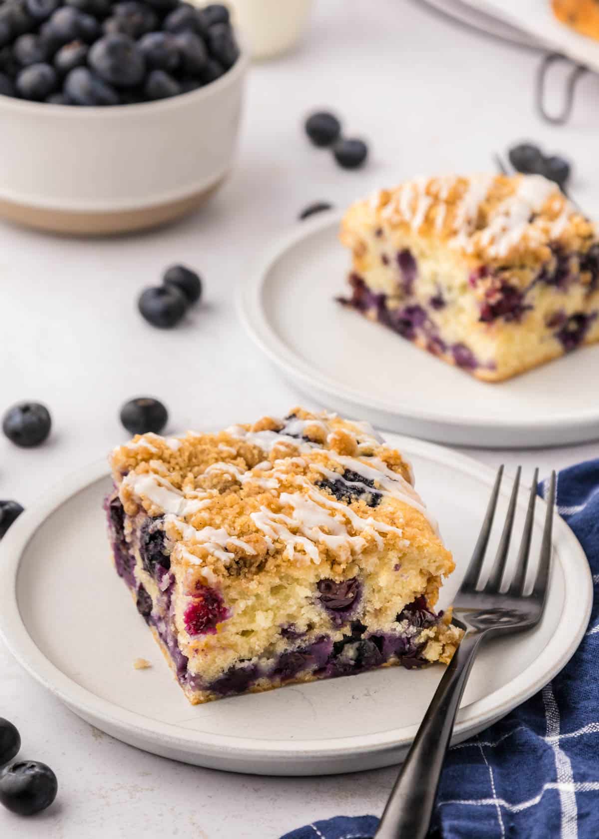 A slice of blueberry coffee cake on a plate with a fork.