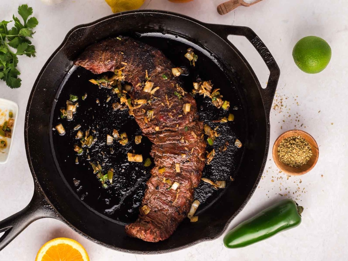 A flank steak in a cast iron pan.