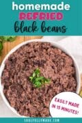 Homemade easy refried black beans recipe pin in a white bowl with cilantro.