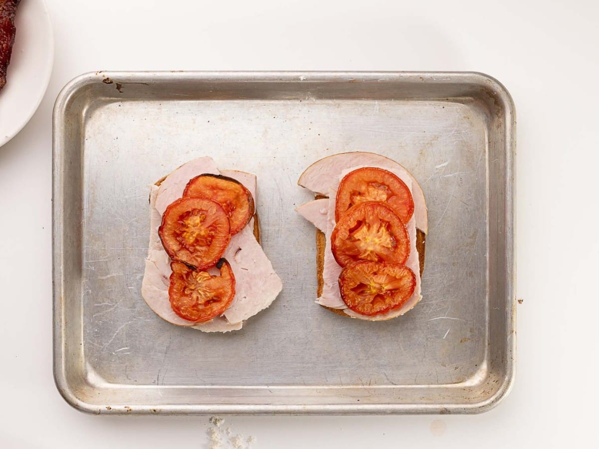 A baking sheet is set out in a step to making Hot Brown. Here is the toast, turkey and tomatoes.