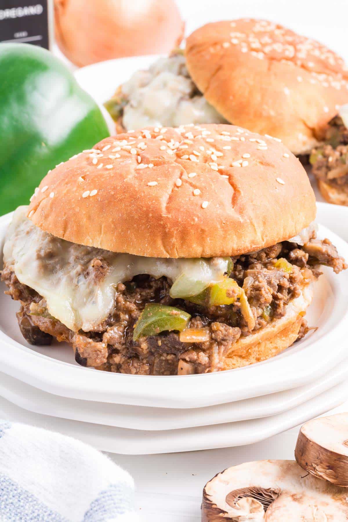 A philly cheesesteak sloppy joe on a bun set on a white plate.