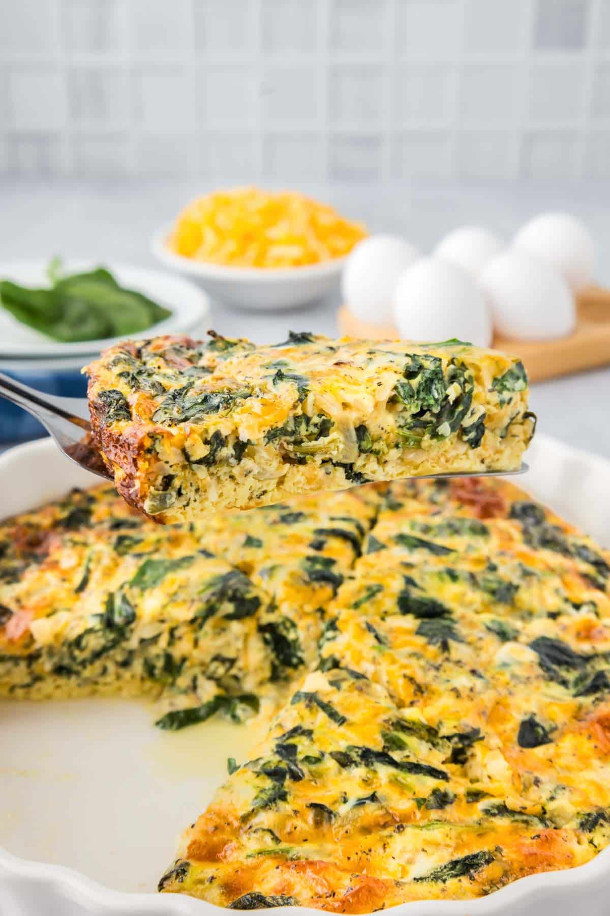 A slice of quiche being removed from the pie dish.