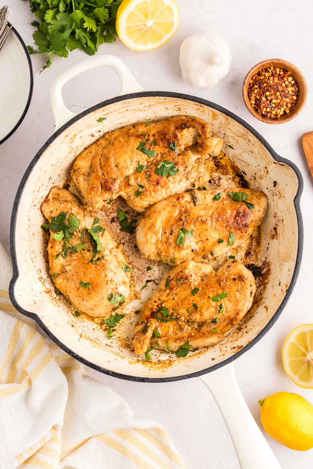 Chicken in a cast iron enamel pan cooked and topped with cilantro.