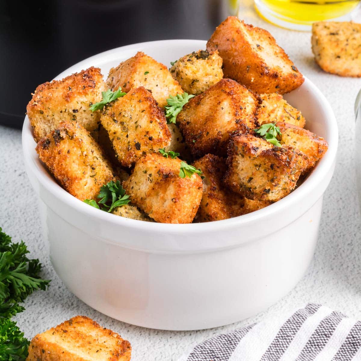 Homemade croutons in a white bowl garnished with fresh parsley.