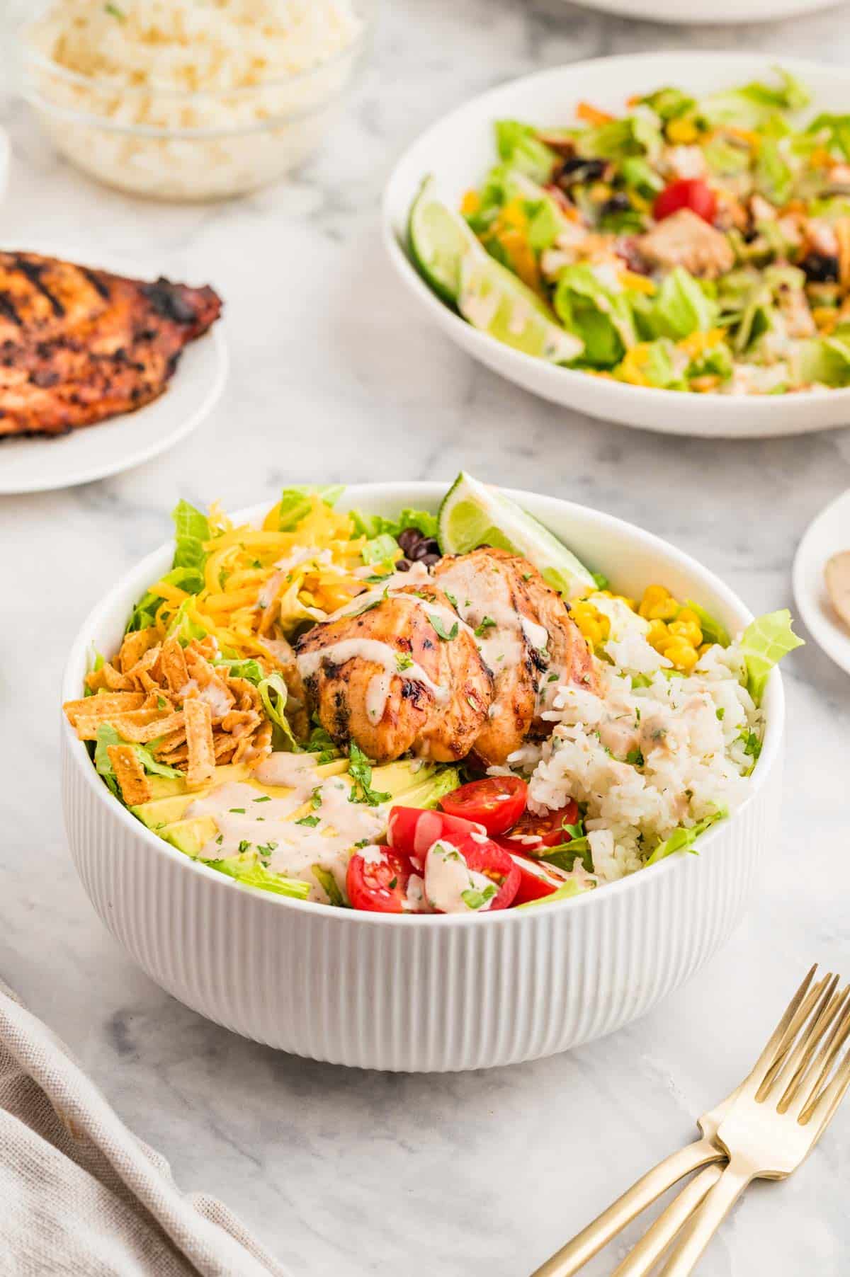 A white salad bowl filled with bbq chicken and a bbq lime dressing.