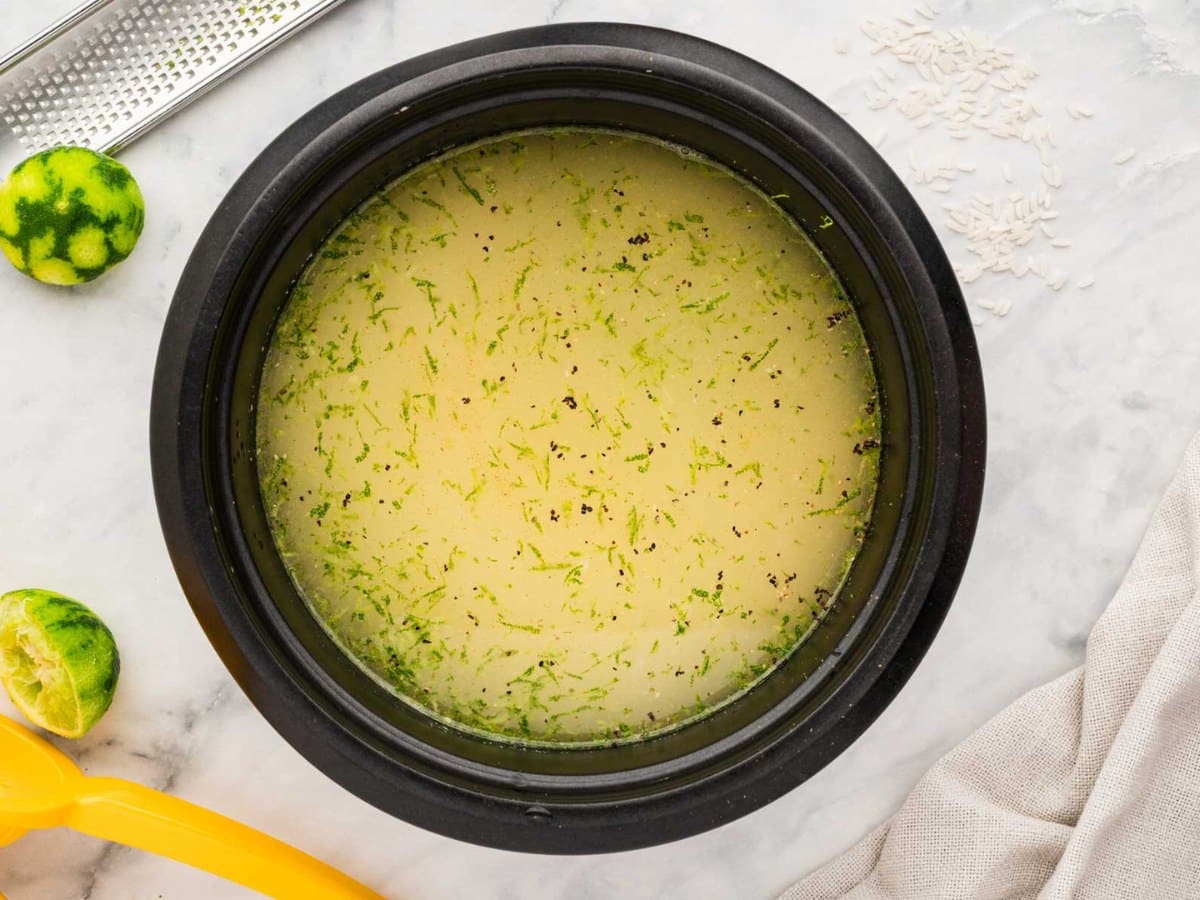 Rice in a rice cooker with lime juice, zest, broth, cilantro and cumin.