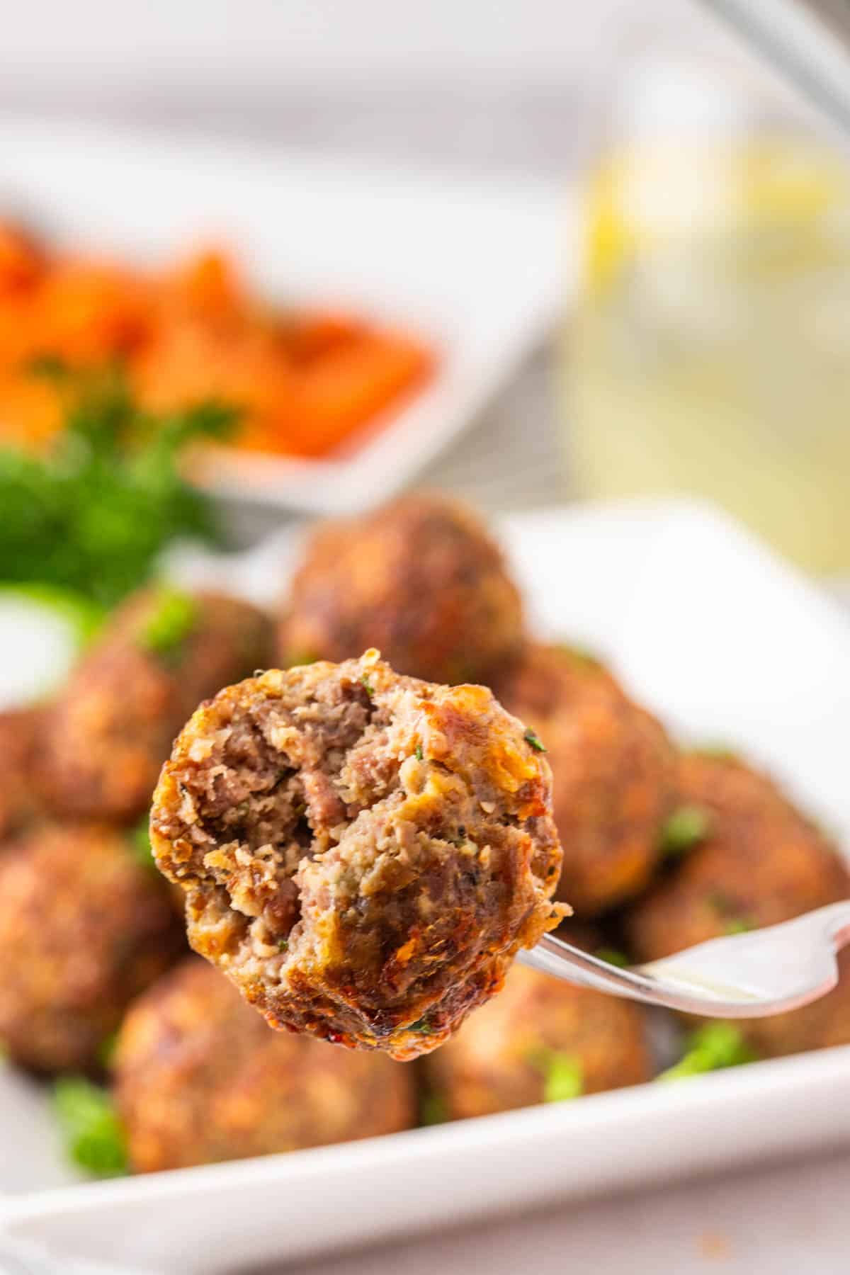 Eight fort picking up a meatball with a bite taken out of it.