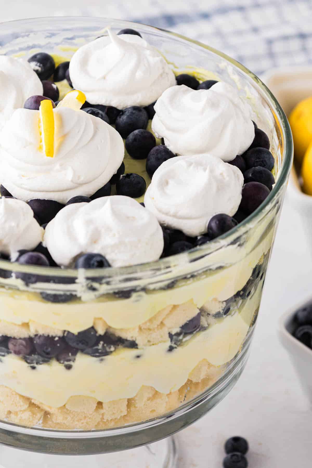 A lemon blueberry trifle in a glass trifle bowl with a stand.