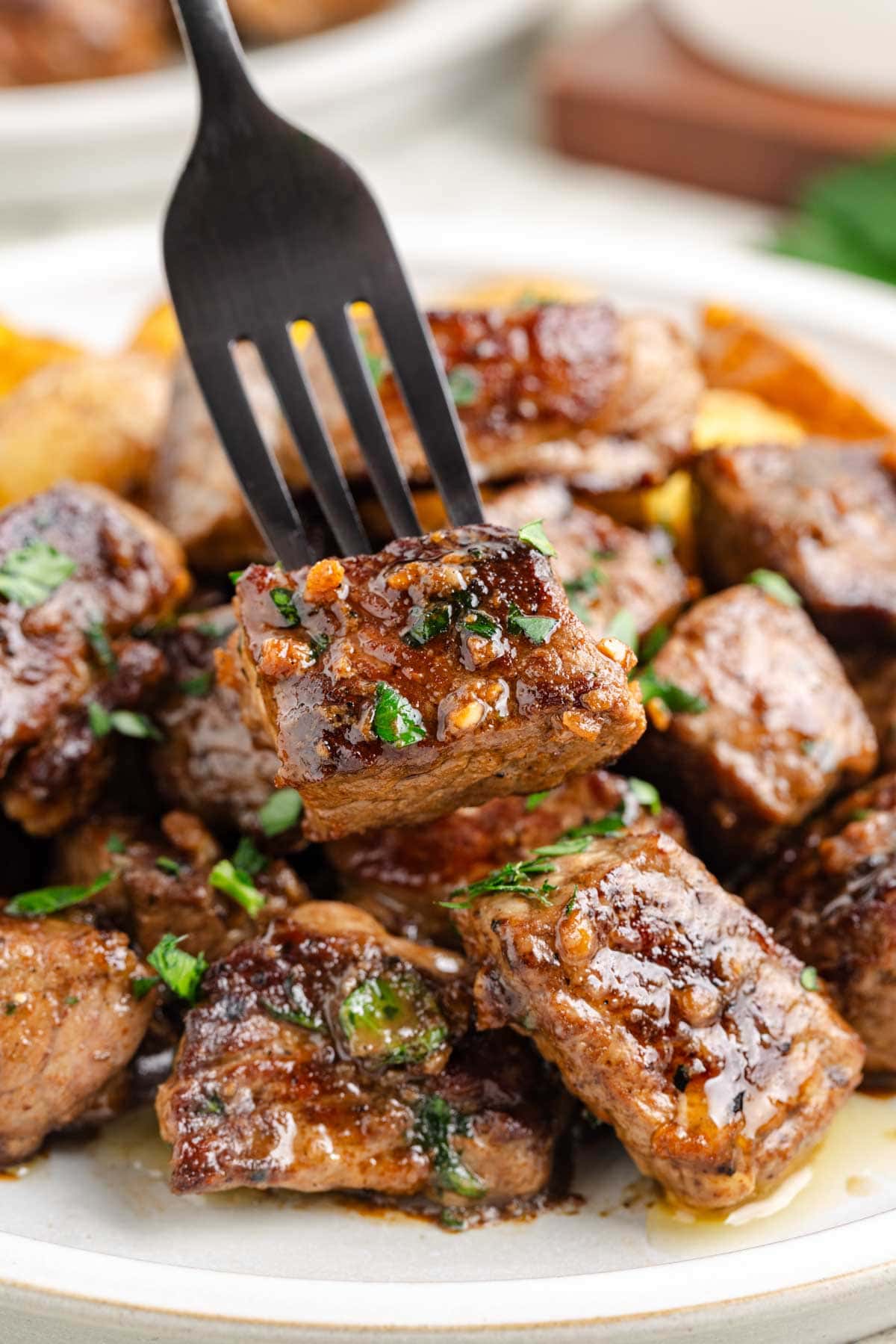 A black fork on a white plate with cubed potatoes.