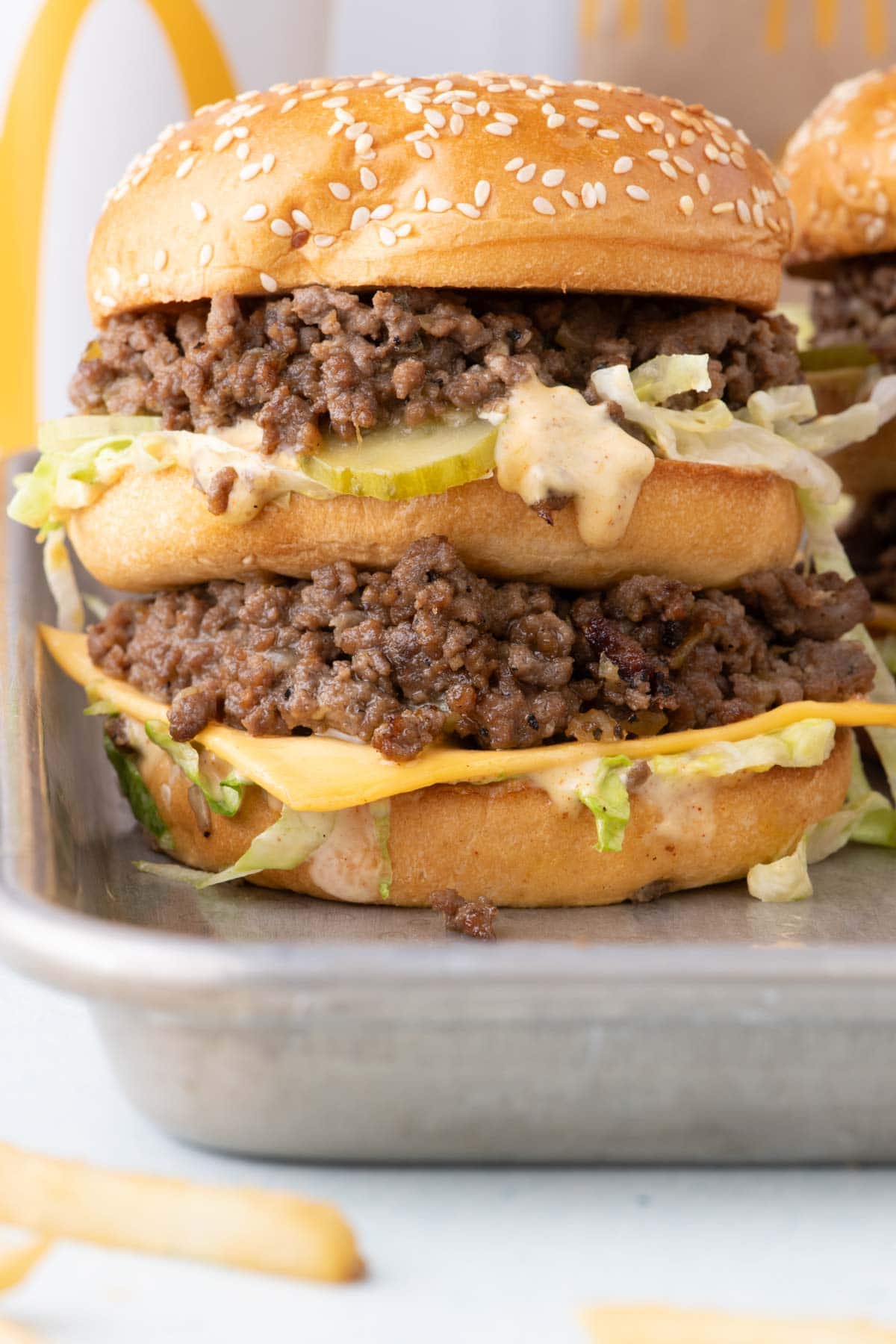Side view of a tall big mac sloppy joe with an extra bun in the middle.
