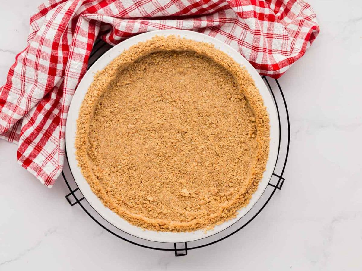 A baked graham cracker pie crust on a cooling rack.