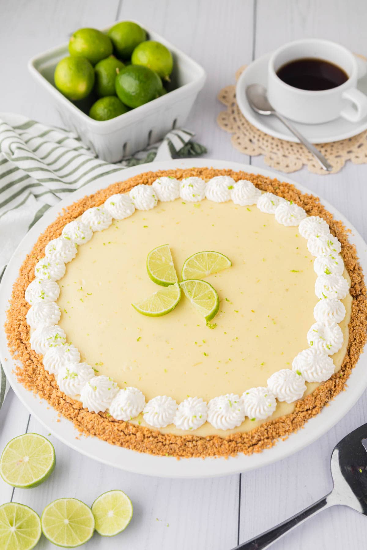 A whole key lime pie garnished with piped whipped cream and key lime slices.