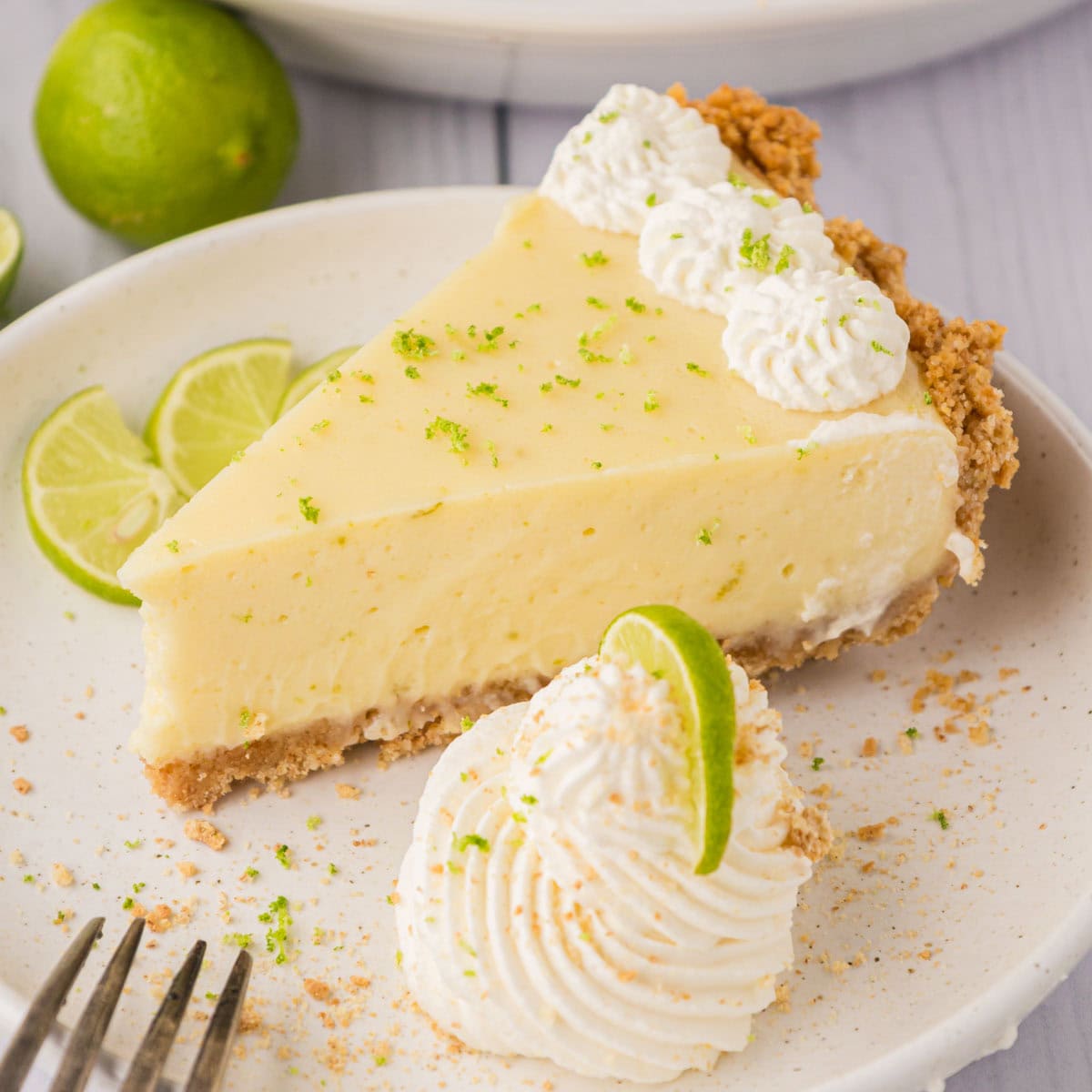 A slice of key lime pie garnished with whipped cream and lime zest.