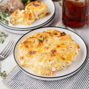 Portion of cheese scalloped potatoes on a white plate.