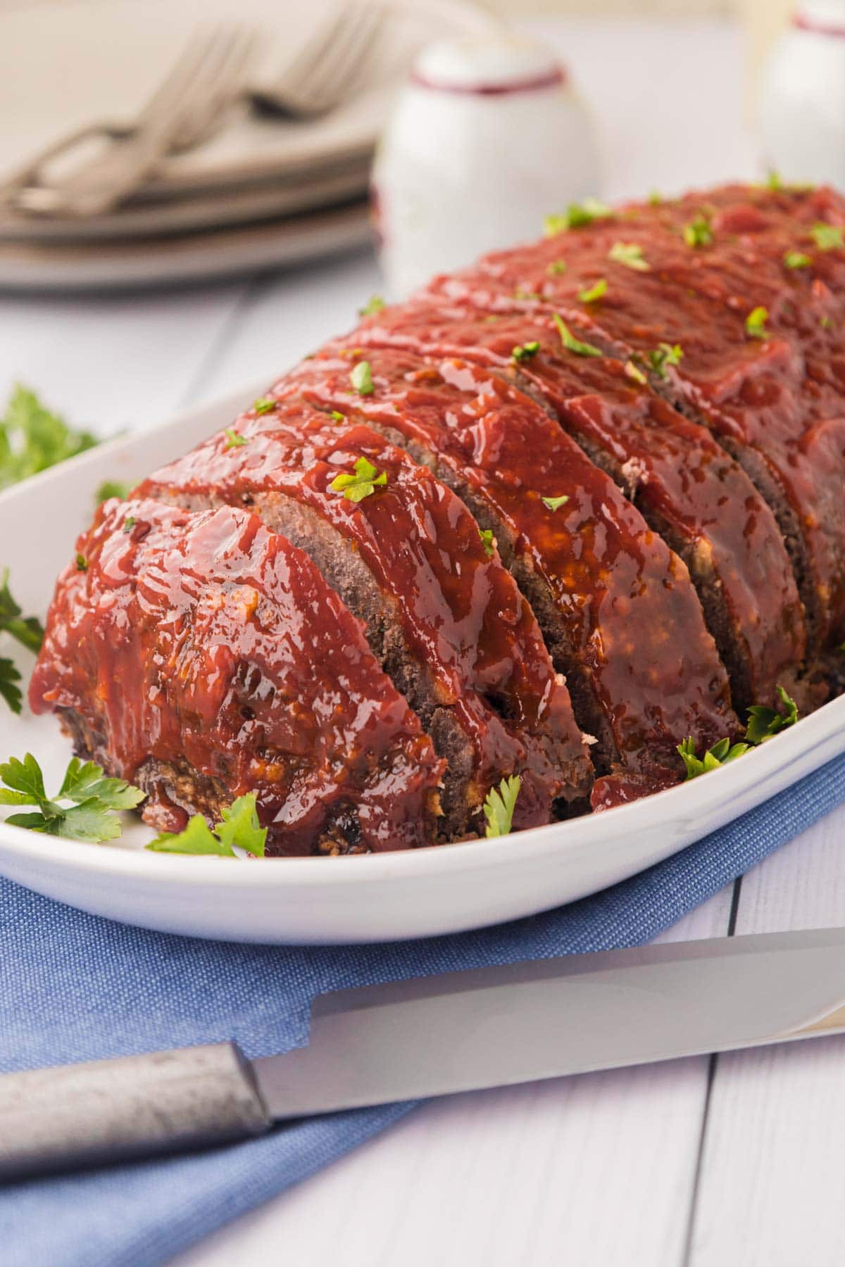 A meatloaf garnished with parsley on a white plate.