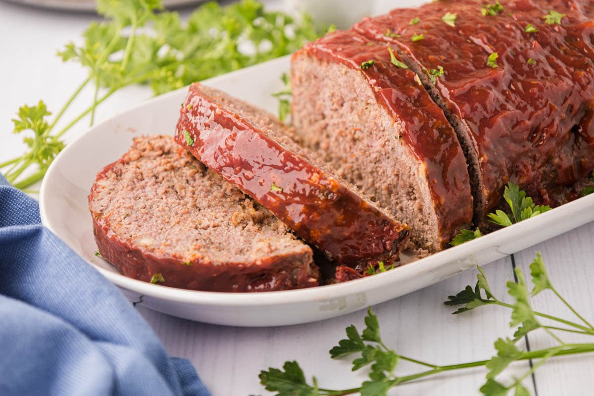 A sliced, classic meatloaf on a white serving platter.