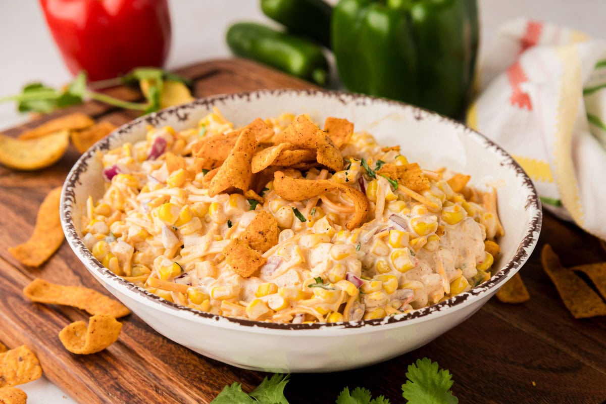 A corn salad with a creamy dressing in a bowl topped with Fritos.