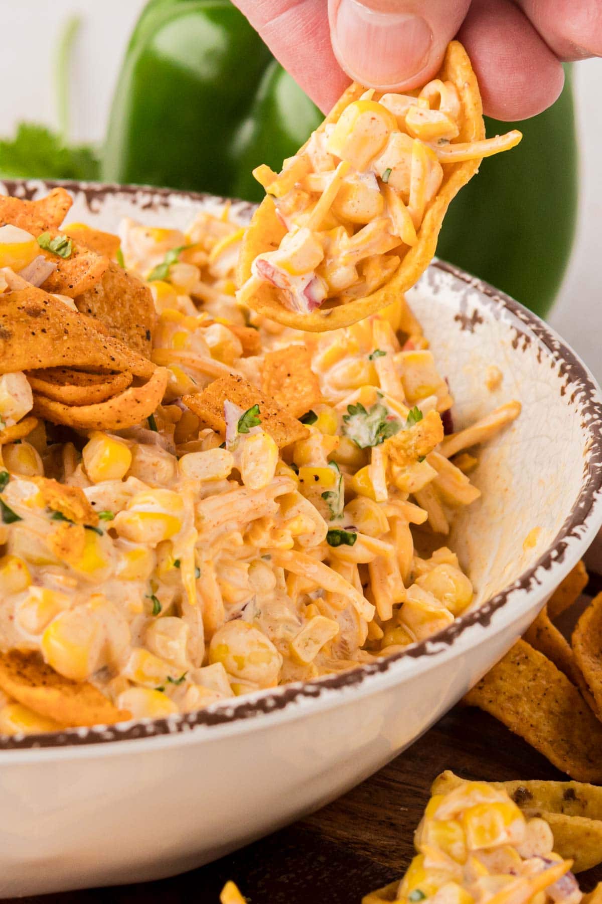 A hand dipping a chip into the taco corn dip.