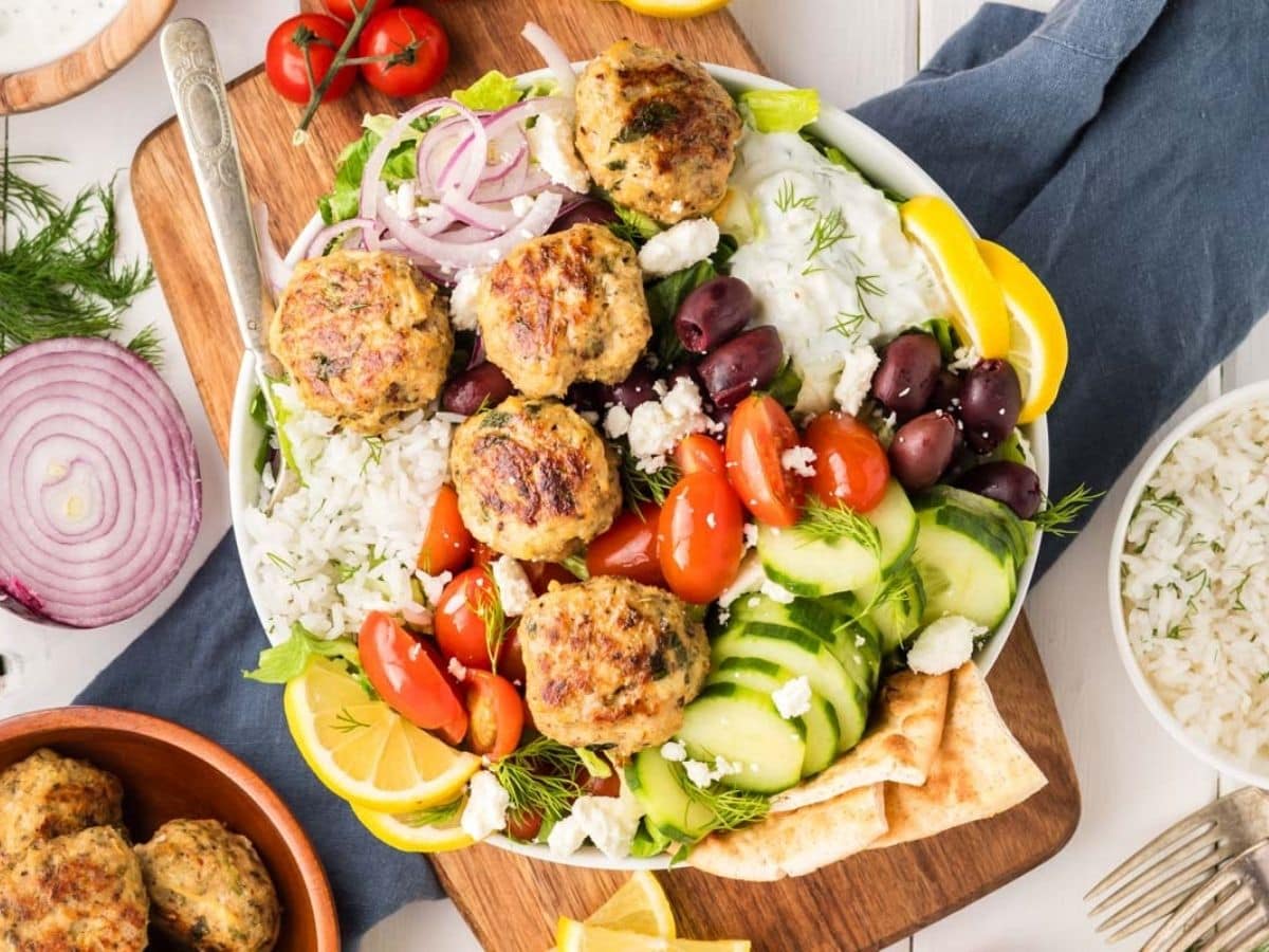 Overhead shot of Greek chicken meatballs served with a variety of veggies on a bed of rice.