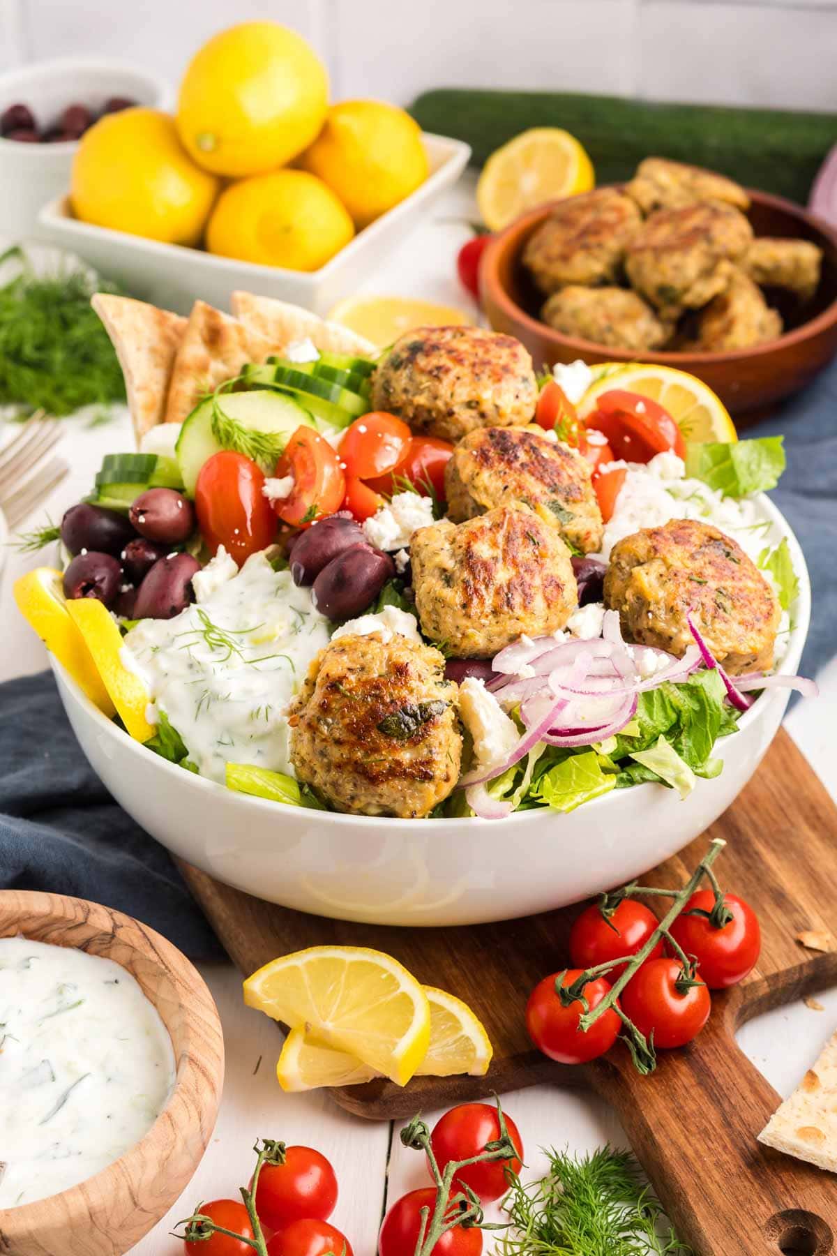 Bowl of rice, veggies, tzatziki sauce and Greek chicken meatballs on top.