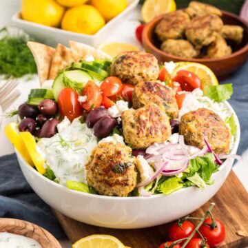 Greek chicken meatballs served on a bowl of rice, veggies and tzatziki sauce.