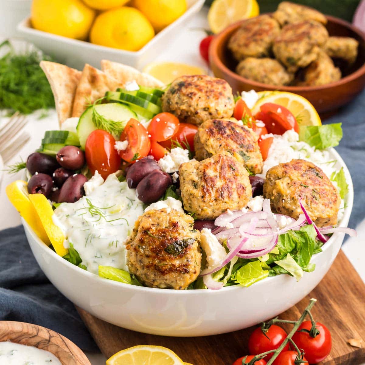 Greek chicken meatballs served on a bowl of rice, veggies and tzatziki sauce.