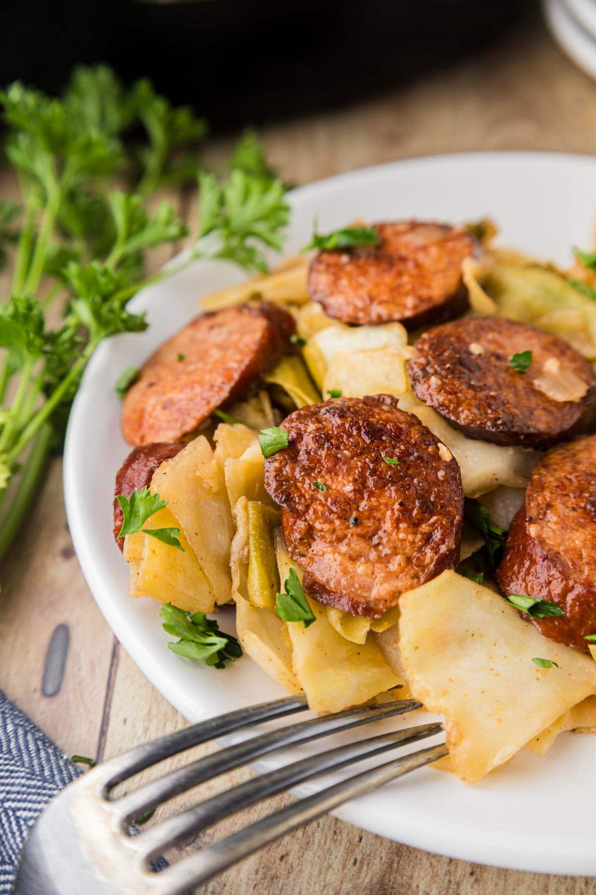 Fried cabbage and sausage served on a plate with a fork.