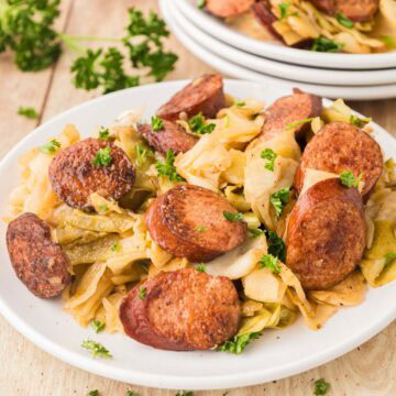 Southern fried cabbage and sausage served on a plate with parsley on top.