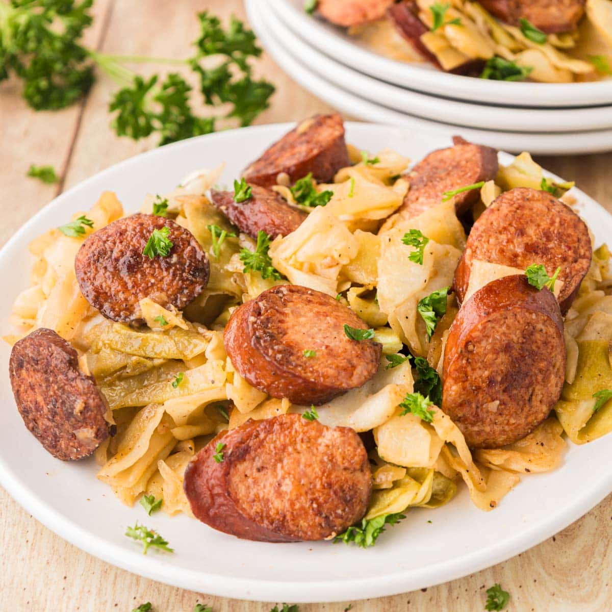 Southern fried cabbage and sausage served on a plate with parsley on top.