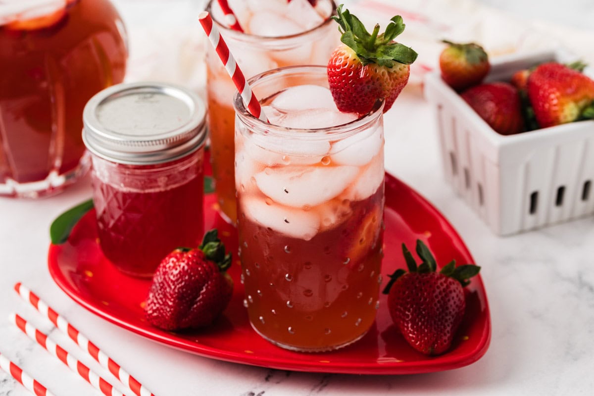 Two glasses of Southern strawberry sweet iced tea on a strawberry shaped platter.