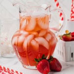 Pitcher of Southern strawberry iced tea next to some fresh strawberries.