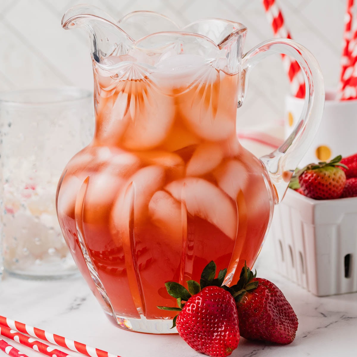 Pitcher of Southern strawberry iced tea next to some fresh strawberries.