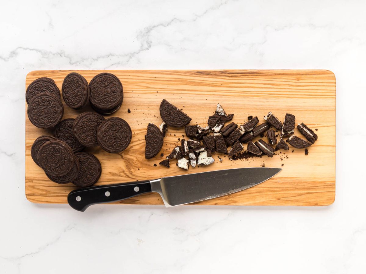 Oreos cut into chunks on a wooden cutting board.